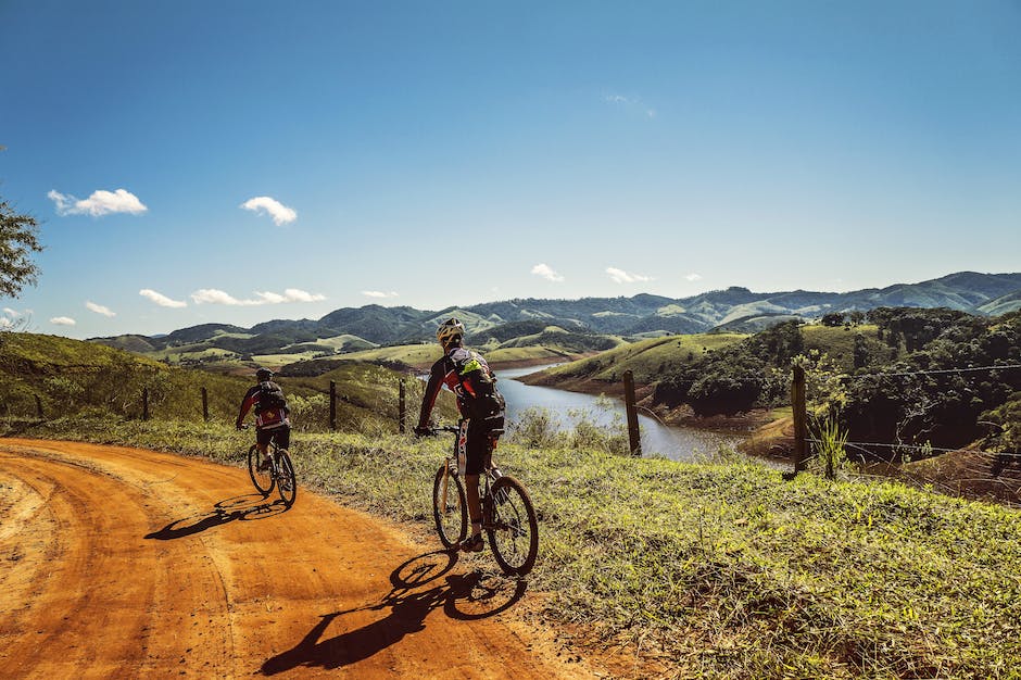 A picture that shows a group of bikers riding on a beautiful trail surrounded by mountains and greenery.