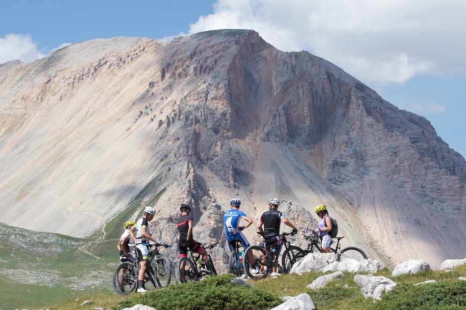 A group of mountain bikers riding on a beginner-friendly trail, surrounded by trees and mountains.